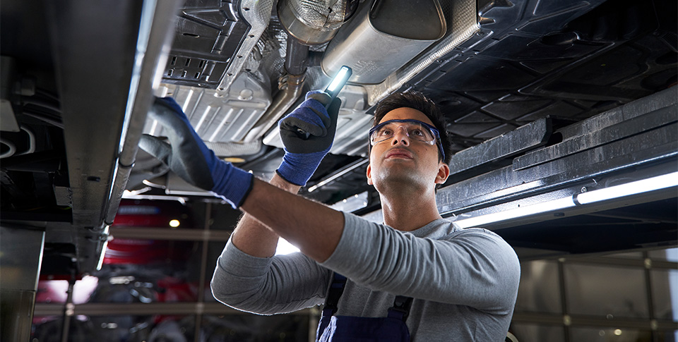 Mechaniker unter Fahrzeug der Fahrzeug untersucht