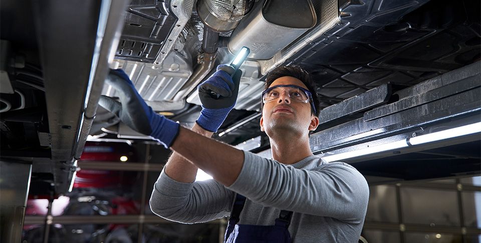 Mechaniker unter Fahrzeug der Fahrzeug untersucht